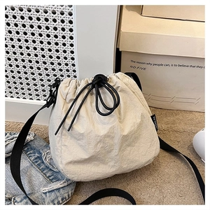 Detail of cream drawstring bucket bag with black strap and nylon fabric texture