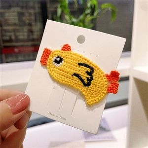 Detail of yellow knitted fish hair clip for girls secured on white display card