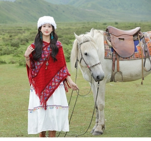 Ethnic red knitted shawl with geometric patterns and tassels on an outdoor steppe setting