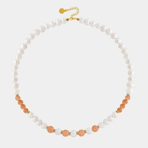 Detail of beaded necklace with white pearls, orange gemstones and golden lobster clasp