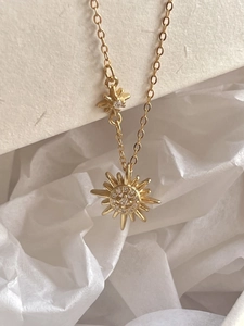 Detailed view of a gold starburst pendant necklace featuring sparkling cubic zirconia