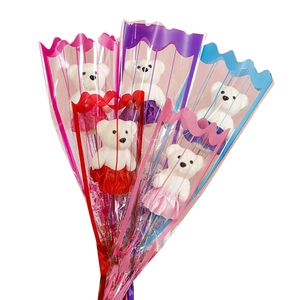 Detail view of five plush bears in colorful silk skirts wrapped as a gift bouquet