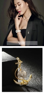 Detailed view of nautical anchor brooch with white crystals and gold plated finish