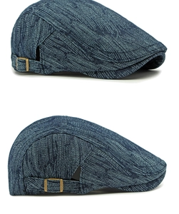 Detailed view of dark blue denim flat cap featuring adjustable copper metal buckle and texture