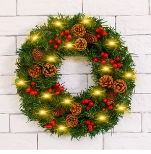 Détail d'une couronne de Noël avec pommes de pin, baies rouges et lumières LED chaleureuses