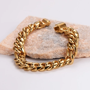 Polished gold vacuum-plated Cuban link bracelet for men on light pink stone display