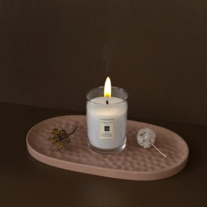 Close-up of a DIY striped resin tray under a burning candle in a cozy home setting
