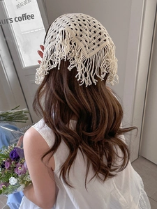 Close-up of cream crochet knit bandana with hollow floral pattern and fringe trim