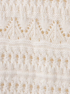 Close-up of the complex crochet knit pattern and soft hollow details on the mini dress