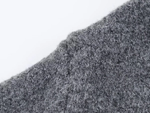 Detailed macro view of the grey fuzzy knit fabric texture and soft wool fibers