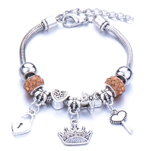 Detail of silver charm bracelet with crown, heart lock and orange rhinestones