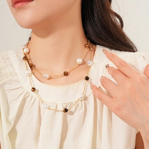 Close-up of double-layer necklace with golden chain, baroque pearls and tiger eye stone