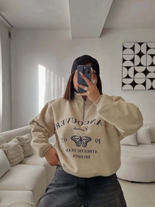 Détail d'un sweat col zippé vintage beige avec imprimé papillon et finitions bords-côtes