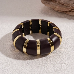 Detail view of bold brown acrylic and gold metal wide bracelet on textured background