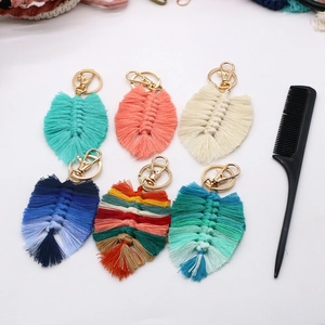 Flat lay of handmade macrame feather keychains in six colors with a styling comb
