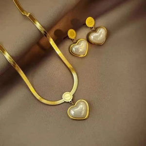 Detail of gold heart pendant and earrings set on silk with Love engraving