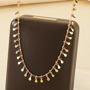 Detail of gold drip glaze water drop pendant necklace on a brown jewelry box