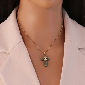 Close-up of a green natural stone cross pendant on a gold snake chain necklace for women