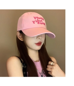 Detail of pink embroidered baseball cap with Sleepy And Hungry text on a model