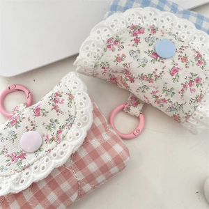 Close-up of pink and blue floral lace earbuds cases with hanging hooks and snap buttons