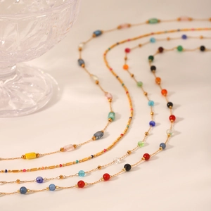 Close-up of golden stainless steel necklaces with colorful natural stone beads and charms