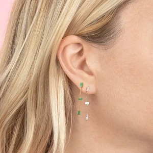 Detail showing long tassel gold earrings with green and white rectangular gemstones