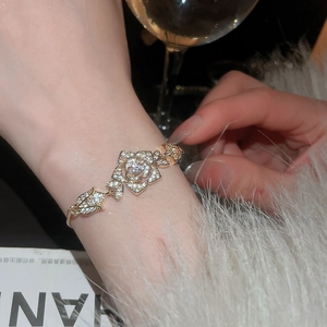 Detailed macro view of rose-shaped gold bracelet with zircon stones on a female wrist