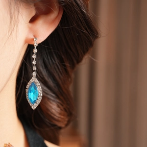 Detailed close-up of blue teardrop pendant earrings with sparkling diamond fringe