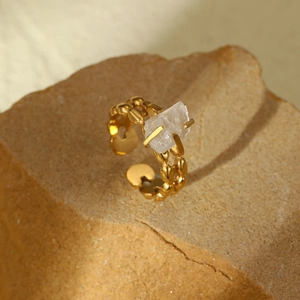 Macro shot of gold stainless steel ring with natural crystal on rustic sandstone