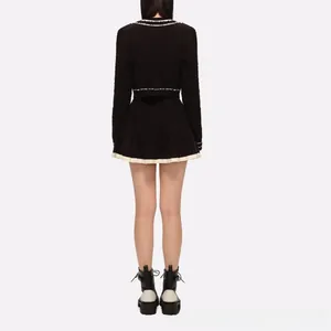 Back view of a black contrast trim cropped jacket and pleated mini skirt set