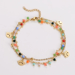 Detail of double-layer gold chain bracelet with colorful beads and evil eye charms