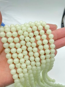 Detailed view of hand-held glowing round beads in a natural pale green jade-like finish