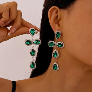 Elegant drop earrings with emerald-colored stones and cross-shaped tassels on model