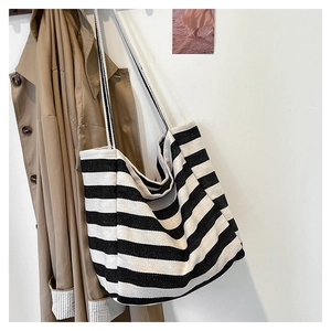 Detail view of large capacity black and white striped canvas tote bag next to khaki trench coat