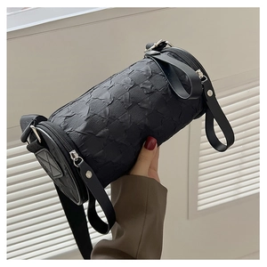 Side view of black cylinder crossbody bag showing pleated texture and wide fabric strap