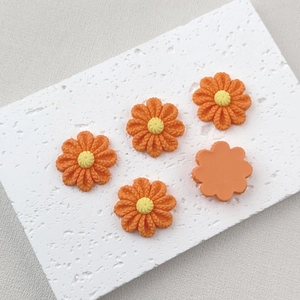 Detailed close-up of orange resin flower charms on a textured white stone surface