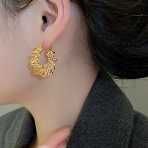 Gros plan de boucles d'oreilles créoles torsadées dorées avec pavé de zircones