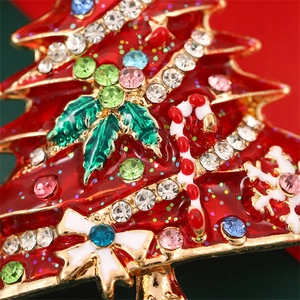 Macro detail of Christmas tree brooch with red enamel, colorful rhinestones and holly leaves