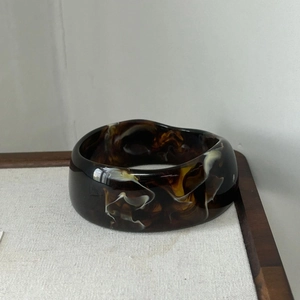 Close-up of thick irregular resin bangle with brown and beige tortoise shell pattern