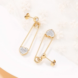 Vue macro de boucles d'oreilles cœur trombone dorées avec cristaux sur dentelle