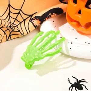 Neon green skeleton hand hair clip with Halloween pumpkin and spider web decorations