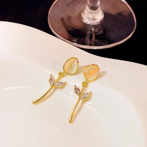 Detail of tulip-shaped gold earrings with cat eye stones and sparkling zircons