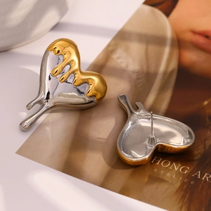 Detail of two-tone liquid metal heart studs in gold and silver with polished finish