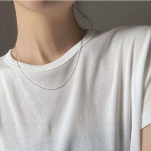 Close-up of minimalist S925 sterling silver snake chain worn by a model on white shirt