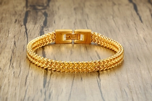 Macro detail of men's gold stainless steel dragon bone chain on vintage wood background