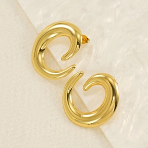 Macro shot of polished gold-plated spiral C-shape hoop earrings on a textured background
