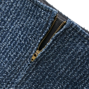 Vista macro del tessuto denim blu scuro con dettaglio della zip in metallo dorato