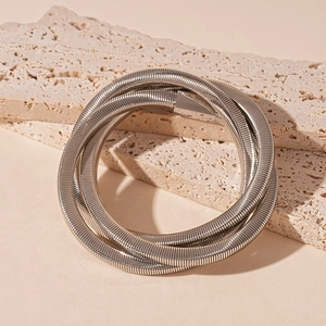 Macro detail of silver layered snake chain bracelet on natural travertine stone background
