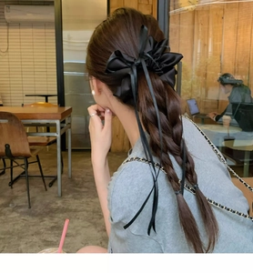 Detail of elegant black satin bow scrunchie with long ribbons on a ponytail