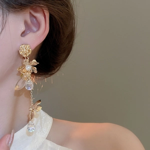 Detail of gold floral tassel earrings with pearls and crystals on a female model